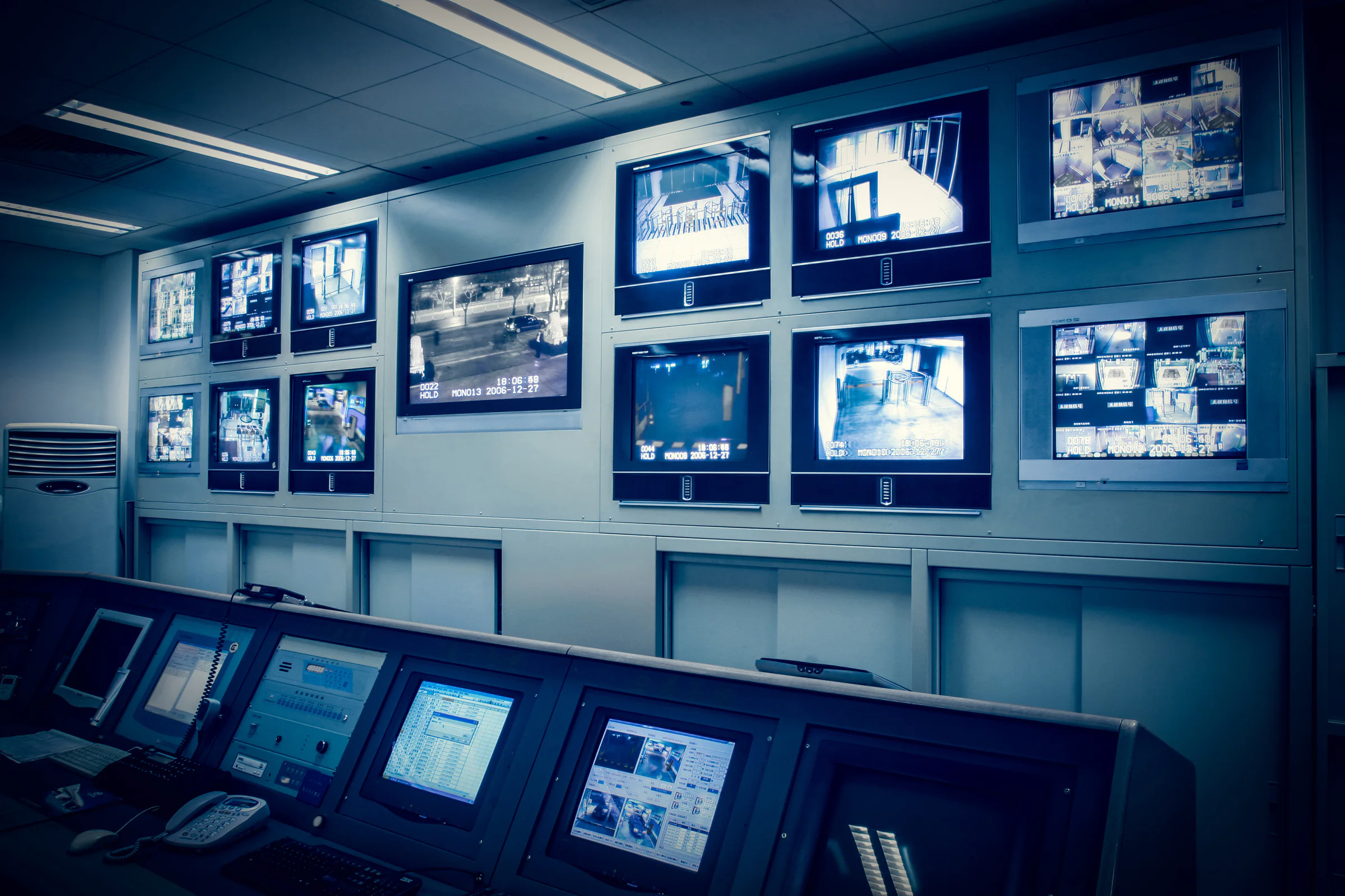 Wall of monitors in a blue-toned control room