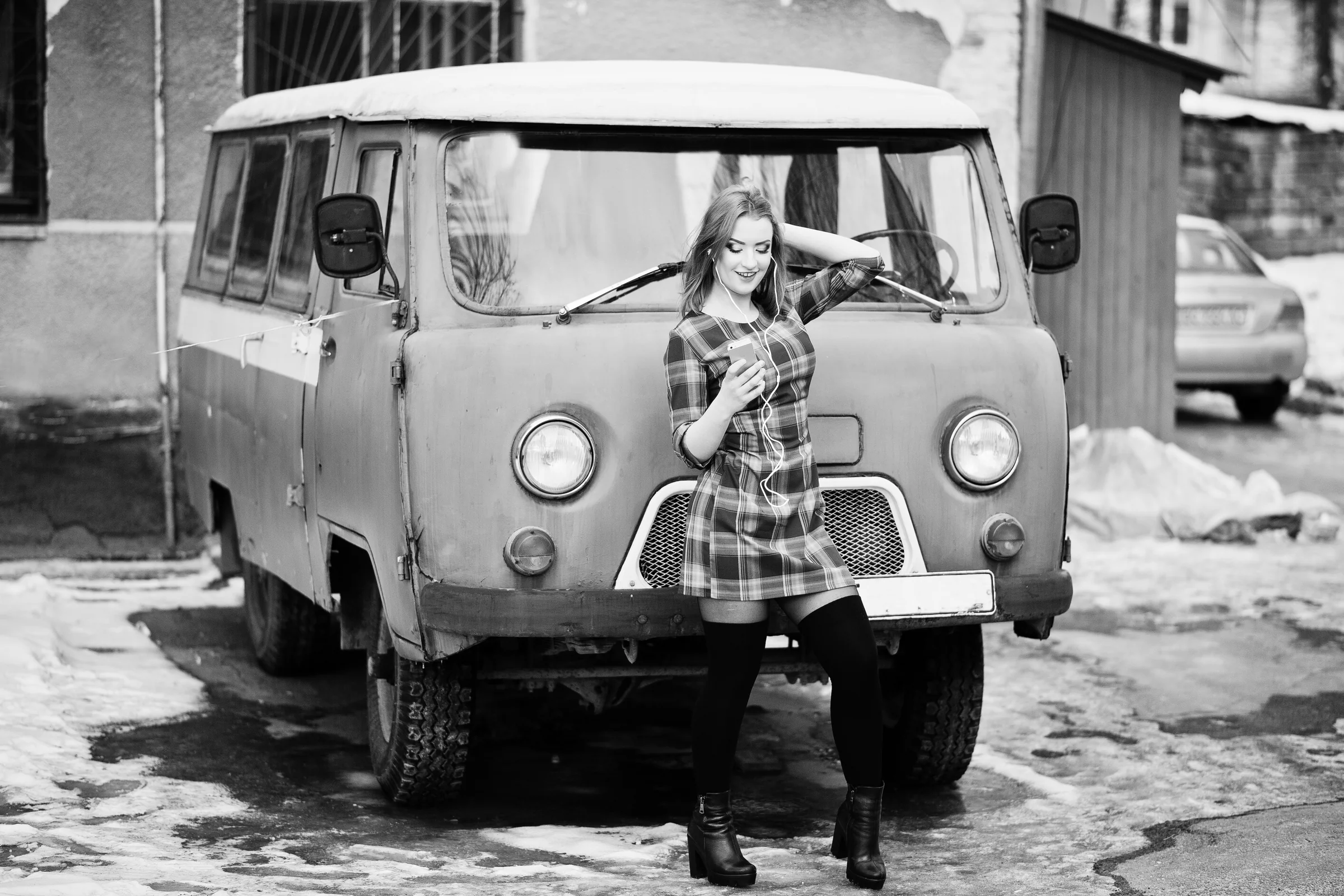 Woman using headphones and a phone beside a vintage van