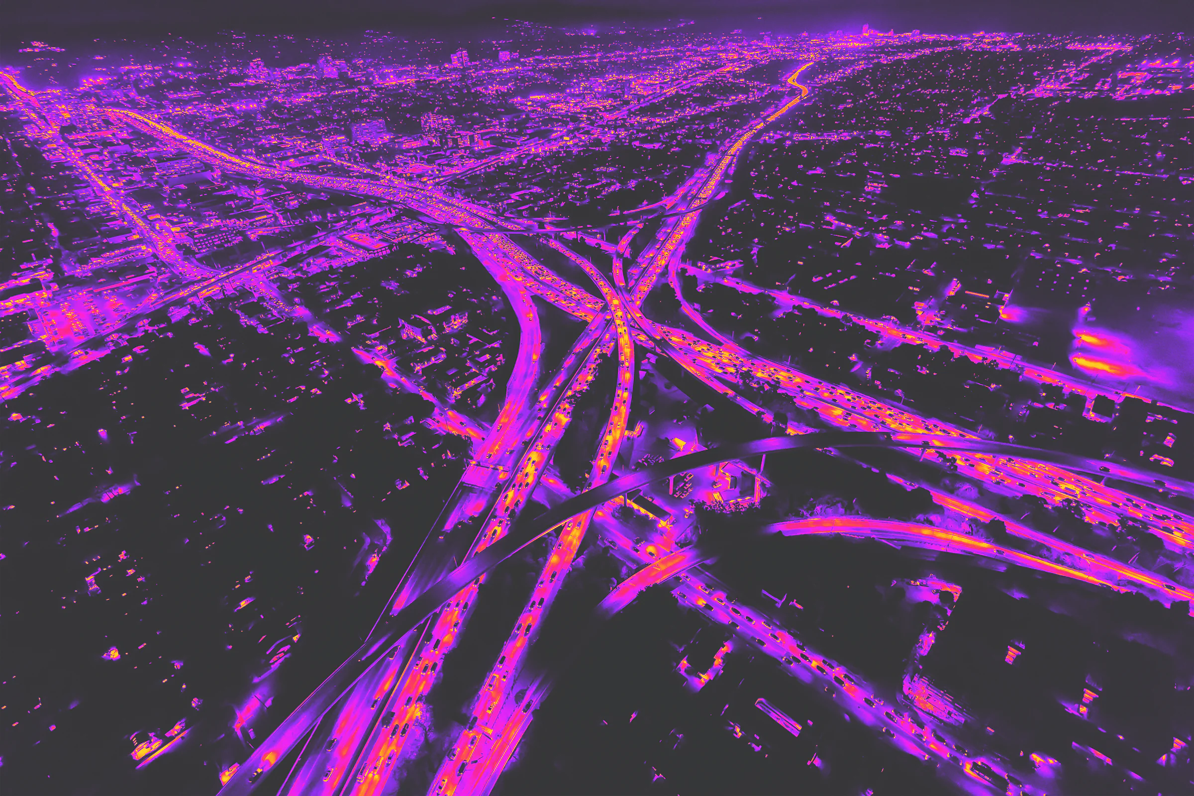 Aerial motorway junction traced in vivid magenta light